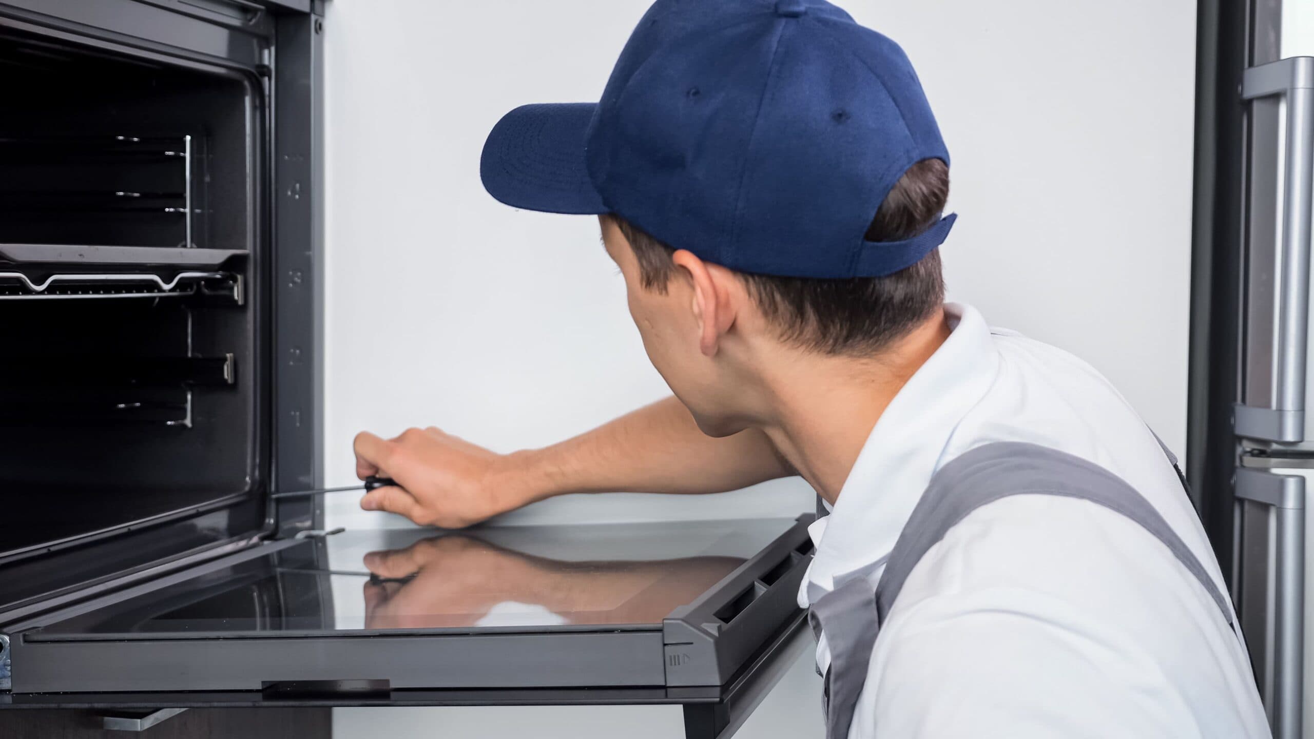 Estufa gas LP estufa gas lp - reparador en uniforme de trabajo atornilla pernos en horno electrico 1 scaled - Estufa gas LP: Guía de mantenimiento básico